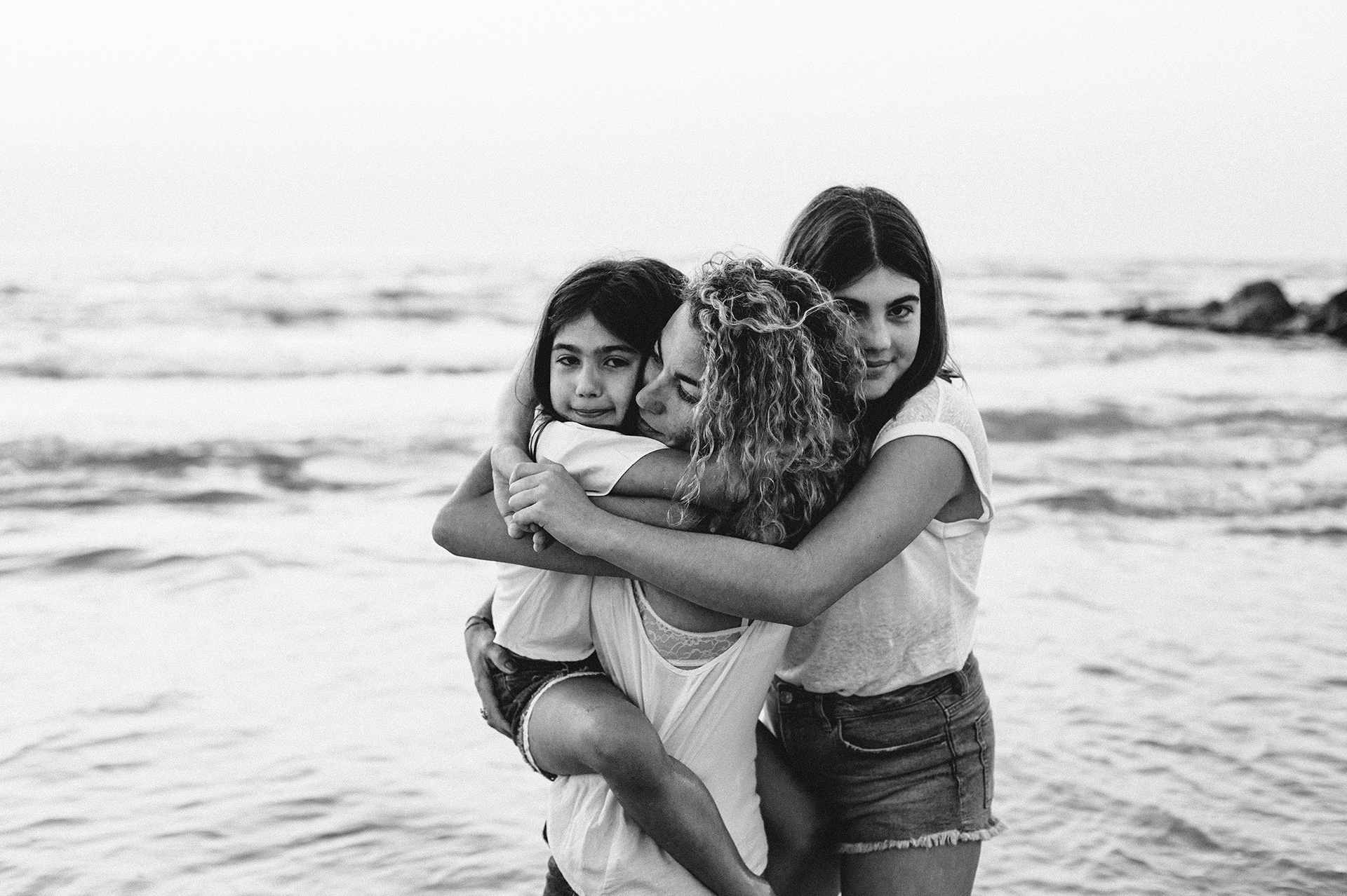 bambine abbracciano la mamma al mare