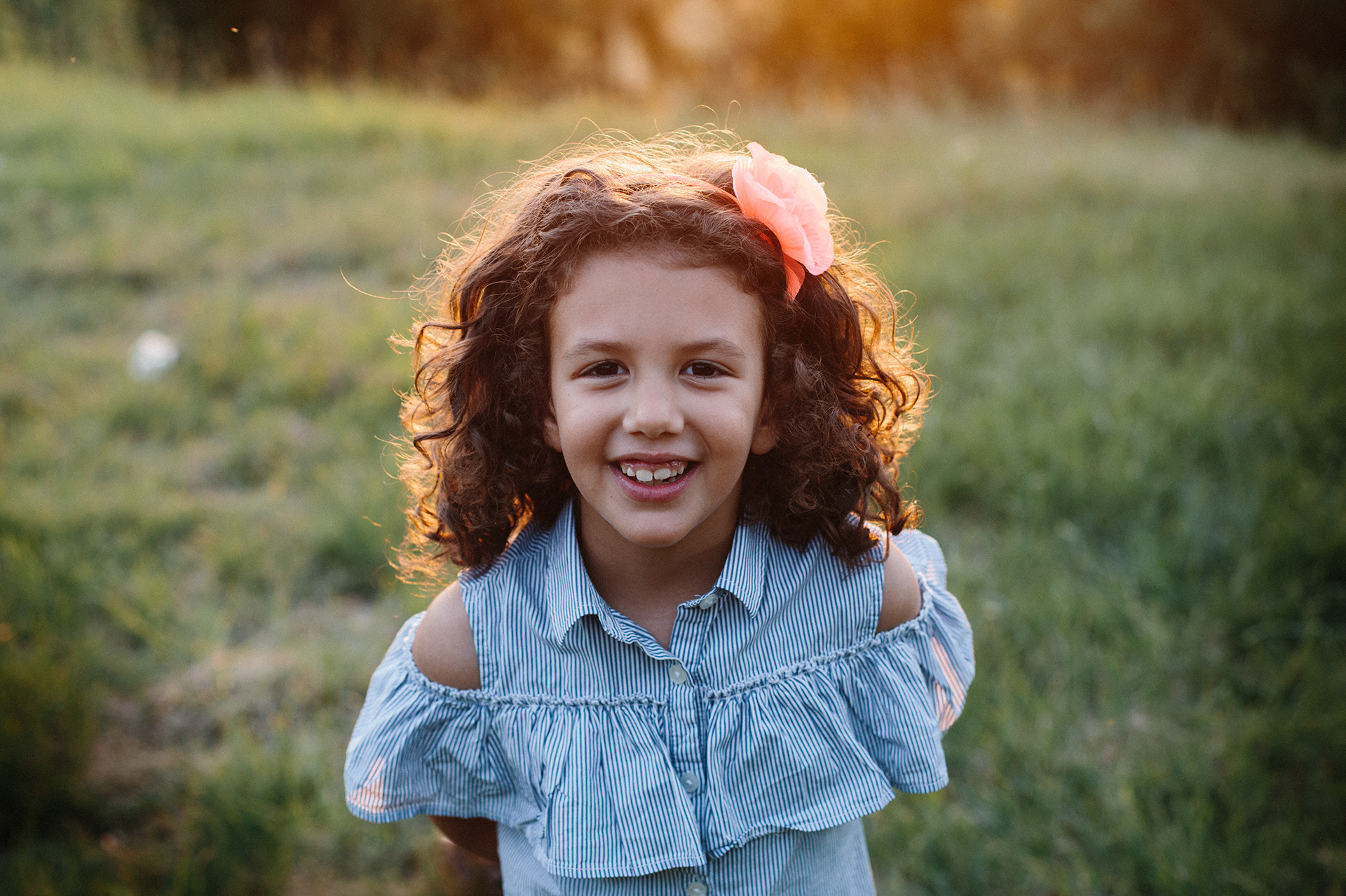 bambina sorride nel prato al tramonto