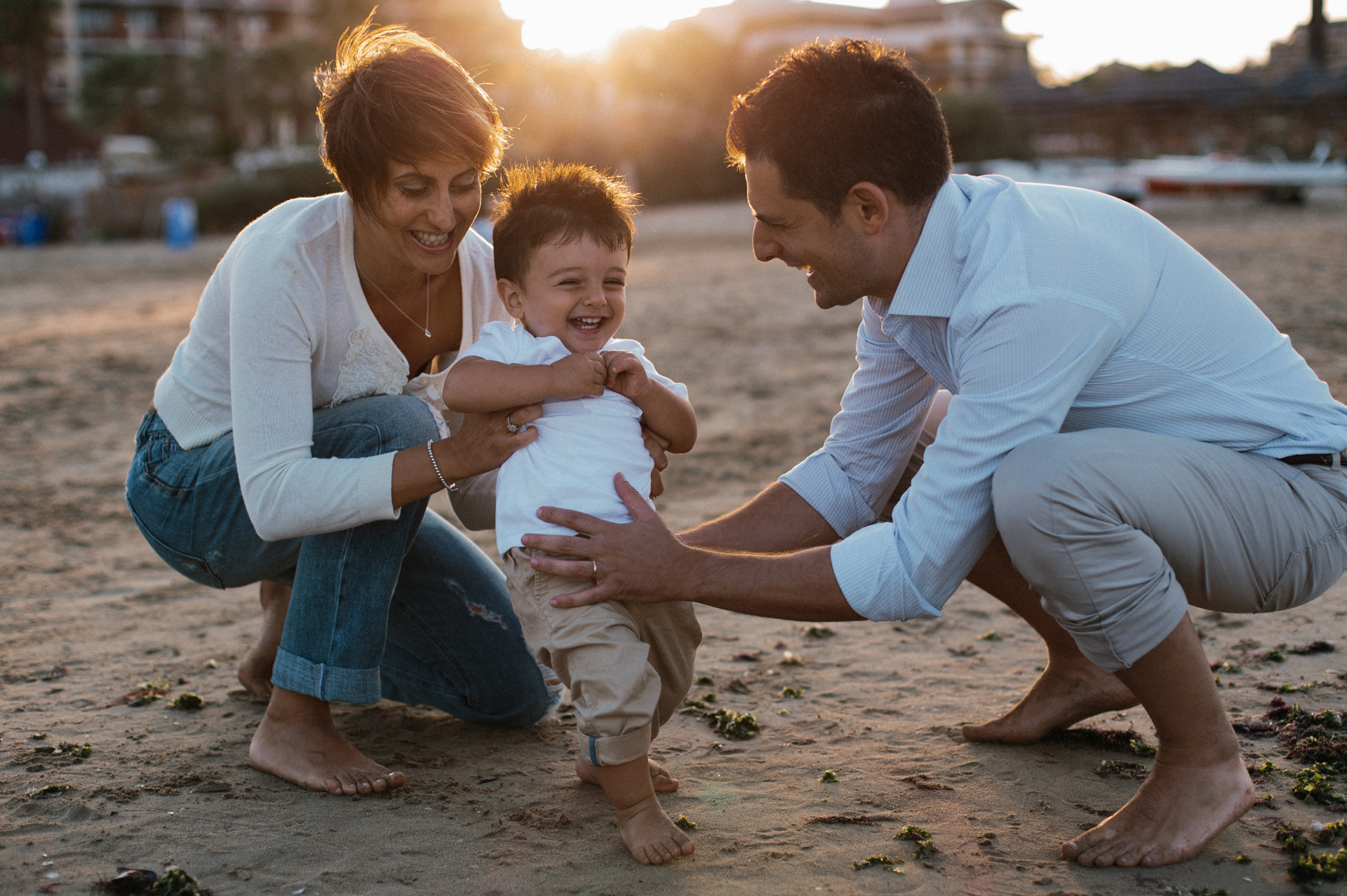 mamma e papà giocano con il bambino in spiaggia