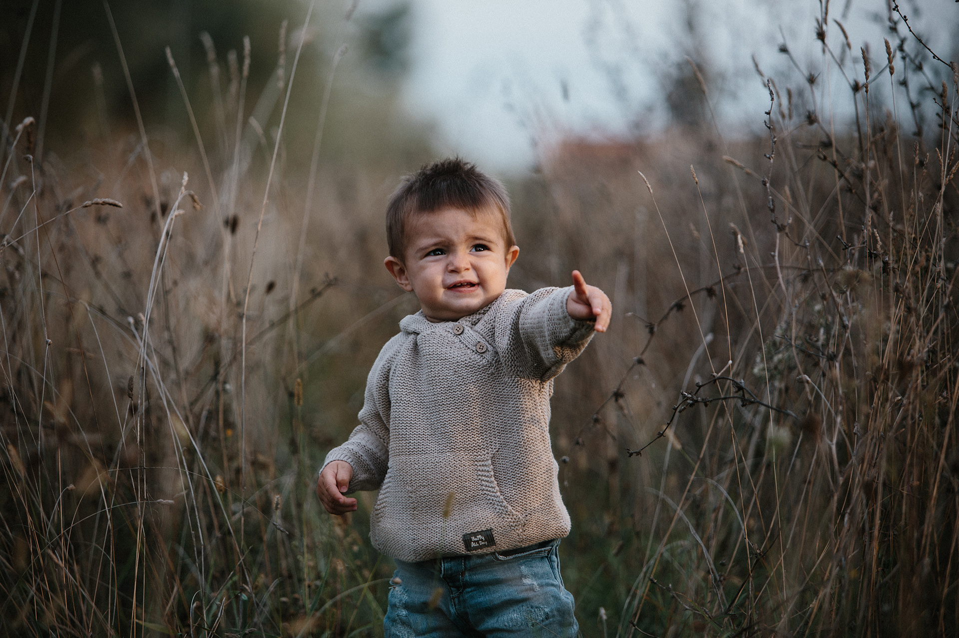 bambino con maglione tra l'erba alta